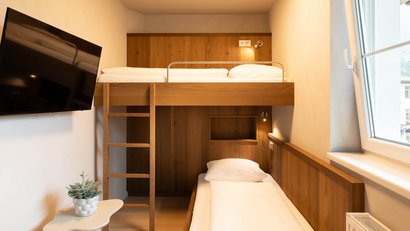 Kleines Zimmer mit Etagenbett aus Holz, Fernseher und Fenster