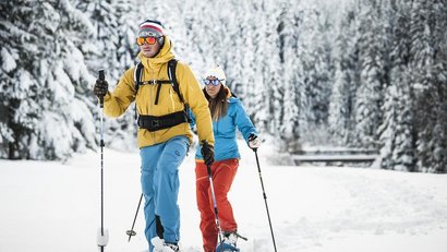 Zwei Personen beim Schneeschuhwandern im verschneiten Wald