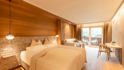 Gemütliches Hotelzimmer mit Doppelbett, Sofa und Balkon mit Bergblick