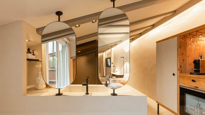 Modern living space with two oval mirrors and open kitchen shelving