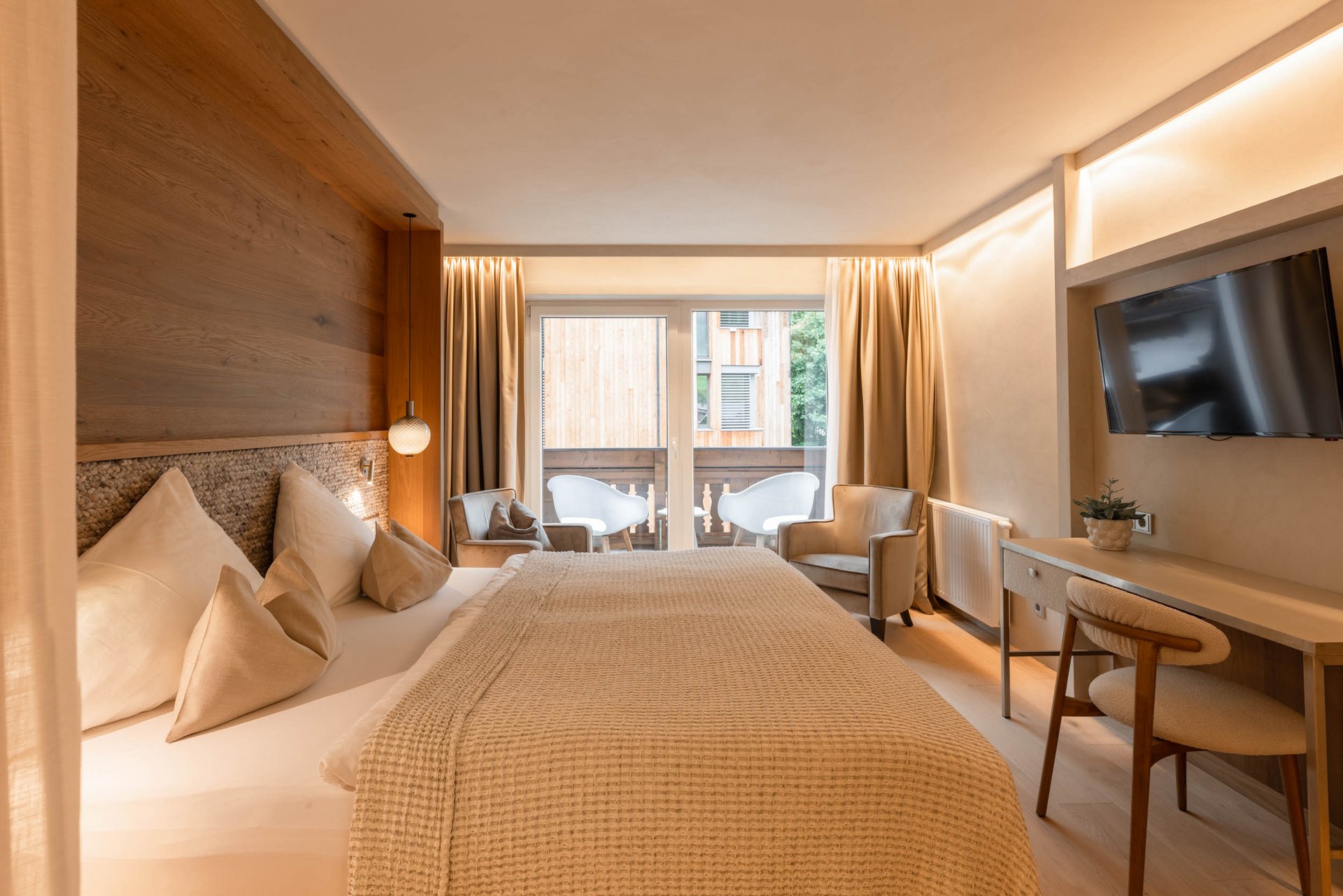 Bright hotel room with comfortable bed, terrace, and wall-mounted TV