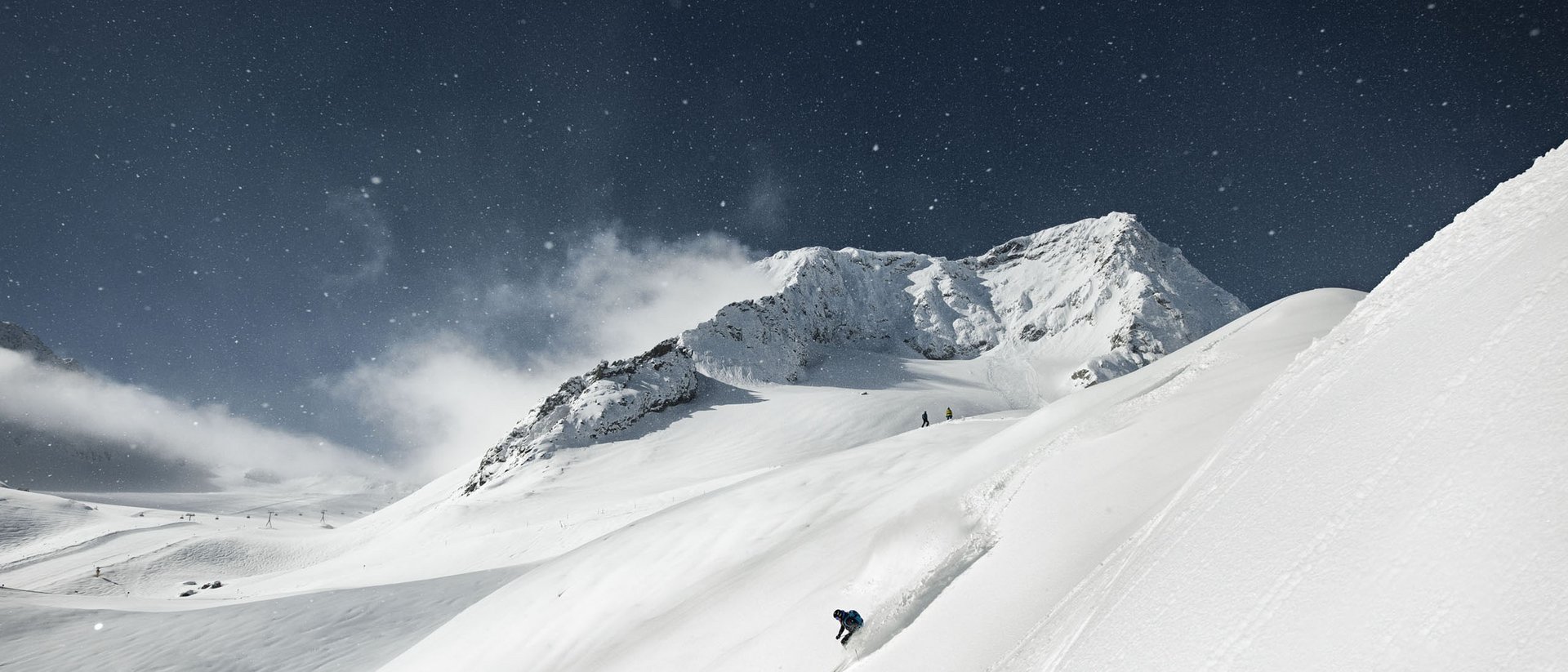 Skier descending a snowy mountain slope under a clear sky