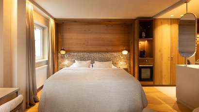 Gemütliches Hotelzimmer mit Doppelbett und Holzverkleidung an der Wand