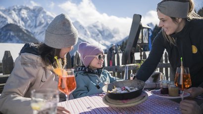 Familie isst draußen in den Bergen bei sonnigem Winterwetter