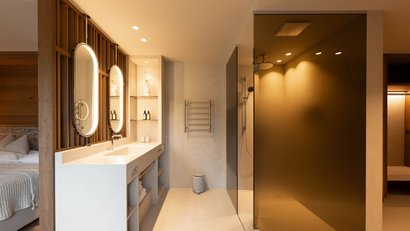 Modernes Badezimmer mit beleuchteten Spiegeln und Glasdusche neben Schlafzimmer