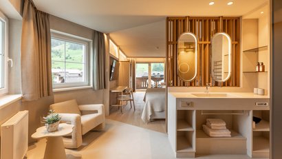 Modernes Hotelzimmer mit Sitzbereich, Doppelbett und Waschtisch mit Spiegeln